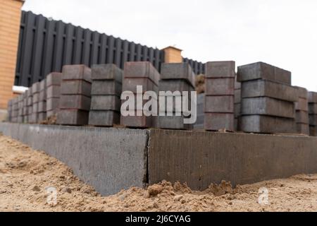 Pose de pavés en béton gris dans la cour de la maison patio d'entrée. Des maçons professionnels installent de nouveaux carreaux ou dalles pour l'allée, s Banque D'Images