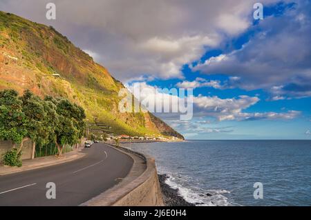 la route côtière se déforme autour de la courbe en arrière-plan les montagnes et l'océan atlantique avec un beau ciel sur l'île de madère, portugal Banque D'Images