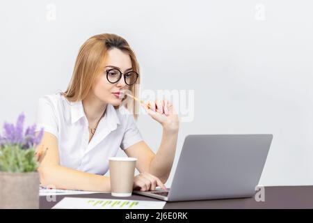 Portrait d'une femme blonde travaillant sur un ordinateur portable depuis le bureau Banque D'Images