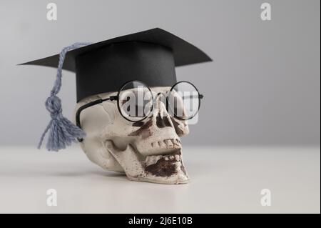 Crâne en plastique avec bonnet et lunettes universitaires. Banque D'Images