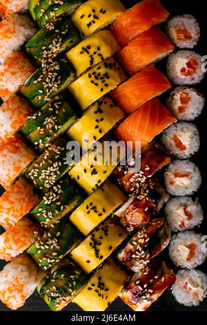 Assortiment de sushis japonais sur fond noir. Cadre alimentaire asiatique ou japonais Banque D'Images