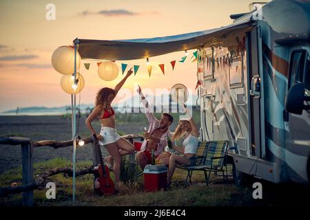 Jeunes amis heureux à côté de campeurs s'amuser pendant un voyage. Banque D'Images