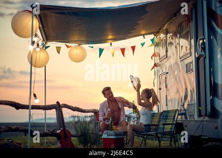 Jeune homme et femme heureux à côté de campeurs ayant du plaisir pendant un voyage. Banque D'Images