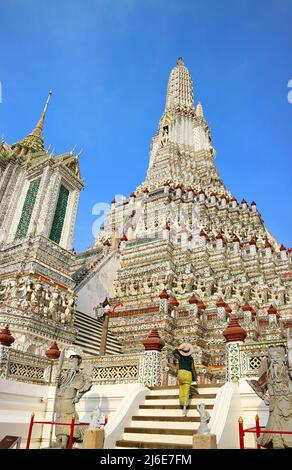 Femme en route vers le Spire central appelée Phraprrang de Wat Arun (le Temple de l'Aube), l'un des monuments emblématiques de Bangkok, en Thaïlande Banque D'Images