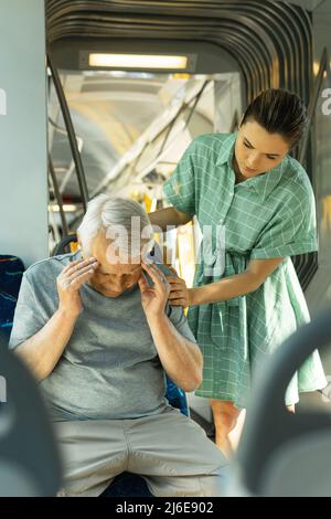 La jeune femme et l'homme âgé se sentent malades avec des symptômes de migraine dans les transports publics Banque D'Images