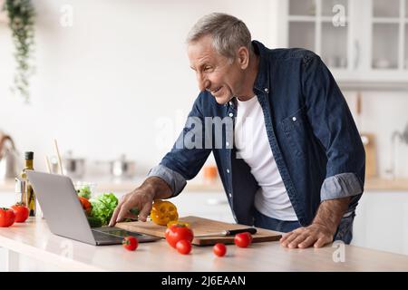 Homme mature en cuisine lisant la recette sur Internet Banque D'Images