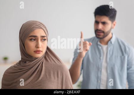 Un homme musulman en colère hurle à une femme déprimée en conflit à l'intérieur Banque D'Images