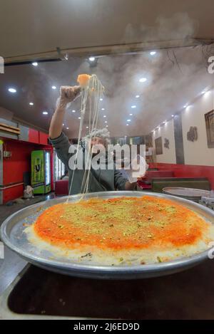 30 avril, Lakemba, Sydney, Australie : la dernière nuit du Ramadan à Sydney, le festival des nuits du Ramadan bat son plein du coucher du soleil de 17,30 h à 02,00 h le lendemain matin. Ici, un homme lève un service de cheesy tentaliche Kenefe Abou (knafeh ou kunafa) pour un client. De longues files d'attente de gens serpentent dans la rue en attendant d'acheter ce et d'autres aliments des nombreuses nations représentées à ce marché chaque soir pendant le festival. Banque D'Images