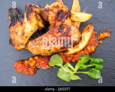 Ailes de poulet grillé avec pommes de terre, sauce piquante et salade de campagne Banque D'Images