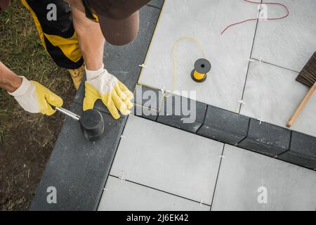 Caucasien professionnel Landscacer bâtiment résidentiel patio fait de briques de béton. Thème de l'industrie de l'aménagement paysager. Banque D'Images