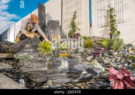 Jardinier caucasien professionnel dans sa finition 40s beau jardin résidentiel de Rockery. Thème de l'aménagement paysager. Banque D'Images