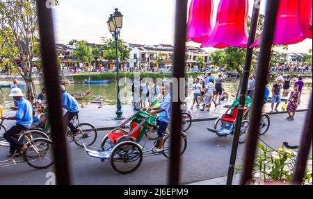 Avis de touristes et la rivière de l'intérieur d'un restaurant à travers les barreaux de la fenêtre. Les voitures passent à vélo pour prendre les touristes pour des manèges. Banque D'Images