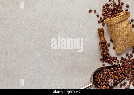 Arrière-plan de café abstrait avec des grains dispersés dans un sac de toile de jute et une spatule rentournés Banque D'Images