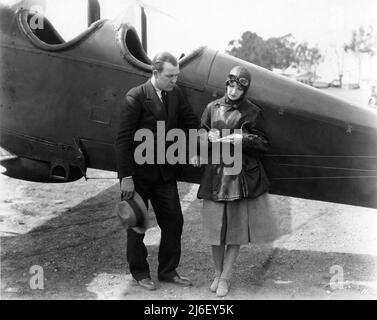 HAZEL KEENER, actrice de film silencieuse, à l'aérodrome militaire de Californie, pose à côté de Bi-plane portant des engins volants vers 1925 Banque D'Images