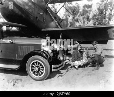 L'actrice de film silencieuse HAZEL KEENER à l'aérodrome militaire de Californie pose avec chien et officier militaire à côté de Bi-plane et Automobilecirca 1925 Banque D'Images