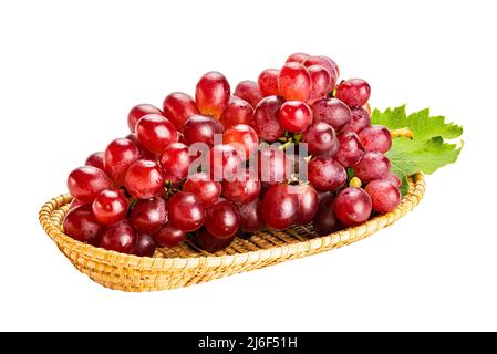 Bouquet de raisins rouges mûrs, raisins Crimson Seedless, avec feuille verte dans un plateau en bambou isolé sur fond blanc avec un chemin d'écrêtage. Banque D'Images