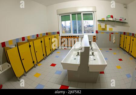 intérieur des salles de bains d'une école maternelle avec des lavabos bas et des cabines de toilette jaunes sans enfants Banque D'Images