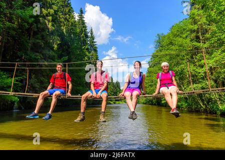 Randonneurs traversant la rivière sur une passerelle Banque D'Images