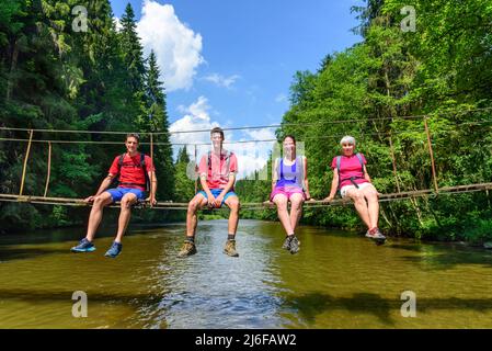 Randonneurs traversant la rivière sur une passerelle Banque D'Images