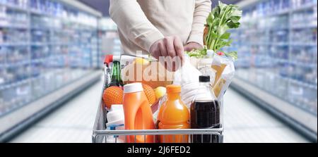 Homme faisant des courses d'épicerie au supermarché, il met une bouteille de lait dans le chariot Banque D'Images