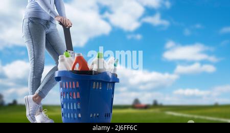 Femme tenant un panier rempli de détergents et paysage vert en arrière-plan Banque D'Images