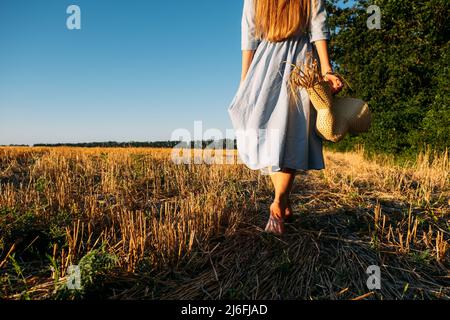 Connectez-vous à la nature, ralentissez, soyez présent, entrez dans vos sens. Femme pieds nus dans la robe bleu de lin marche à travers le champ de blé incliné Banque D'Images