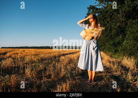 Connectez-vous à la nature, ralentissez, soyez présent, entrez dans vos sens. Femme pieds nus dans la robe bleu de lin marche à travers le champ de blé incliné Banque D'Images
