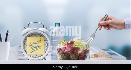 Femme mangeant une salade fraîche et saine pendant sa pause déjeuner au travail Banque D'Images