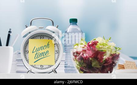 Un bol à salade sain et un pense-bête de l'heure du déjeuner rappel : pause déjeuner au travail Banque D'Images