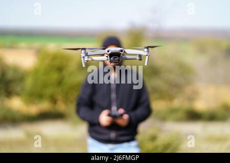 Homme volant un drone devant lui et couvrant son visage. Banque D'Images