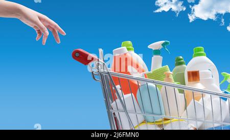 Femme achetant des détergents: Panier plein de bouteilles de détergent et ciel bleu en arrière-plan Banque D'Images