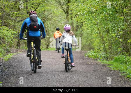 Un homme et deux enfants pédalez sur le Sett Valley Trail, qui relie New Mills et Hayfield dans le Derbyshire. Banque D'Images