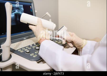 Gros plan de la main d'un médecin radiologue tenant un transducteur à ultrasons et un gel de contact se préparer à un diagnostic. Échographie. USG Banque D'Images