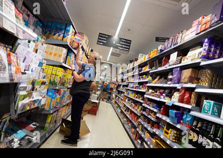 Femme plus âgée employée empilant des étagères avec des boîtes de céréales de petit déjeuner dans Co Op Supermarket allée Royaume-Uni Grande-Bretagne 2022 KATHY DEWITT Banque D'Images