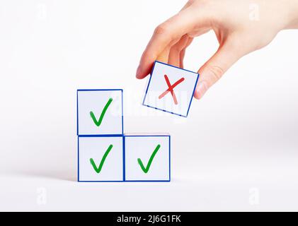 Main de choisir le cube avec la croix au lieu de blocs avec la coche. Décision négative, choix de rejet, concept de mauvaise réponse. Photo de haute qualité Banque D'Images