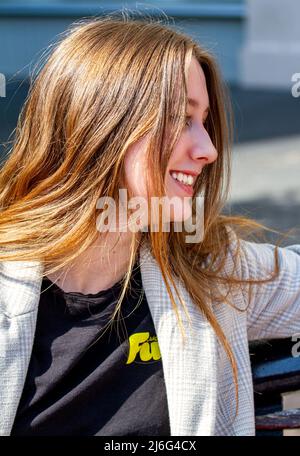 Une belle jeune femme assise à l'extérieur et profitant du soleil d'avril dans le centre-ville de Dundee, en Écosse Banque D'Images