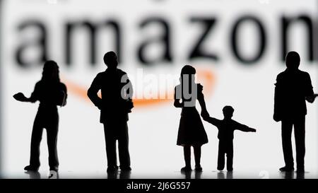 Dans cette illustration, des figurines miniatures se tenant devant un logo Amazon flou sur le smartphone. Banque D'Images