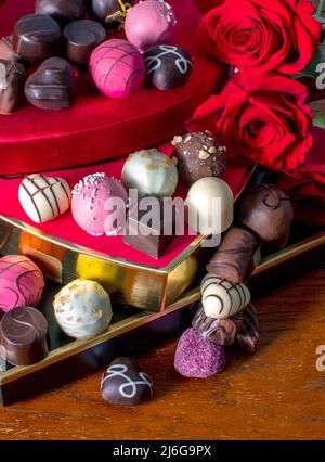 les boîtes de bonbons empilées sont superposées avec de délicieux chocolats fantaisie et des roses rouges Banque D'Images