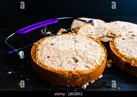 Mise à niveau des gâteaux fraîchement cuits aux fraises : deux gâteaux qui viennent d'être mis à niveau avec un niveleur de gâteau en fil de fer réglable Banque D'Images