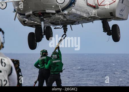 MER DES PHILIPPINES (7 avril 2022) Spécialiste de la logistique le marin Cameron Mudgett, à gauche, de Carlsbad, en Californie, et le spécialiste de la logistique le marin Zachary Overton, de Rancho Cucamunga, en Californie, placez un crochet de chargement sur un Super Puma AS332 sur le pont de vol du porte-avions de la classe Nimitz USS Lincoln Abraham (CVN 72) Au cours d'un réapprovisionnement vertical en mer avec le navire de fret et de munitions du Commandement du Seallift militaire USNS Richard E. Byrd (T-AKE, 4). Abraham Lincoln Strike Group est sur un déploiement prévu dans la zone d'exploitation de la flotte américaine 7th afin d'améliorer l'interopérabilité par le biais d'alliances et d'une partie Banque D'Images