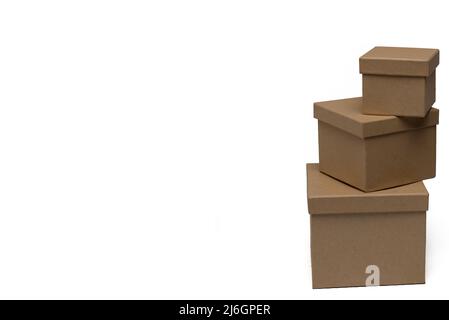 Gros plan de trois boîtes-cadeaux en carton marron empilées de différentes tailles sur fond blanc comme concept pour les cadeaux et les paquets Banque D'Images