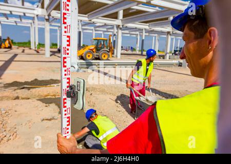 Zrenjanin, en Voïvodine, Serbie - Avril 26, 2018 : Construction Worker holding est la tige de mise à niveau pour aider arpenteur, géographe de mesurer la position, la profondeur. Banque D'Images