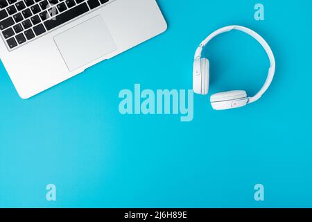 Ecouteurs numériques blancs et clavier compact pour ordinateur portable sur fond bleu Banque D'Images