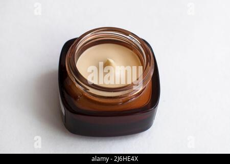 Crème pour le visage dans un pot brun en verre. Cosmétiques pour le visage dans un pot. Contenant de crème hydratante pour le visage sur fond blanc. La mode femme encore la vie. La médecine Banque D'Images