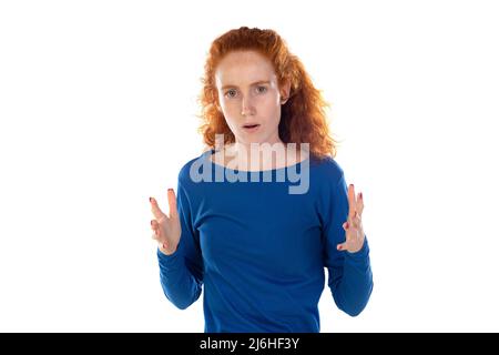 Photo en intérieur d'une jeune femme caucasienne à tête rouge stressée et agacée avec des cheveux bouclés tenant les mains dans un geste furieux fou, criant avec ragea et colère. Banque D'Images