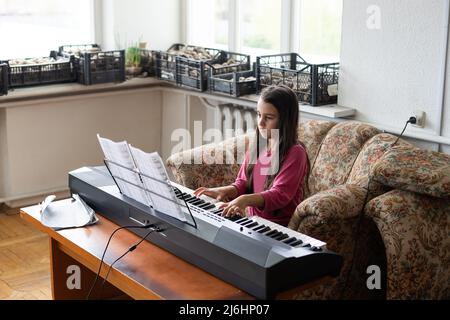 Portrait d'une petite fille triste dans un bâtiment en ruines. Un petit colon joue le piano. Réfugiés Banque D'Images