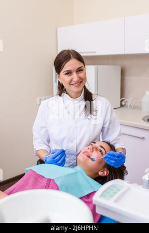 Femme dentiste traite un patient. Une femme dans un masque est assise dans une chaise dentaire dans la clinique. Médecine, santé, art dentaire concept Banque D'Images