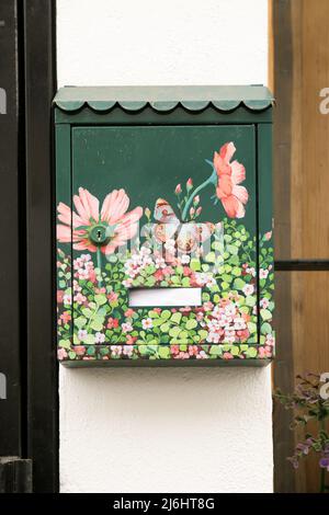 Finestrat, Alicante, Espagne - 23 avril 2022 : boîte aux lettres en métal vert peinte avec des motifs floraux à la porte Banque D'Images