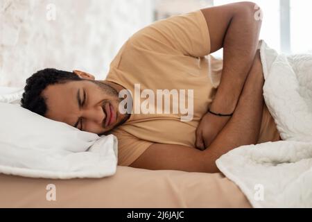 Arabe Guy souffrant de douleur abdominale touchant Tummy dans la chambre Banque D'Images