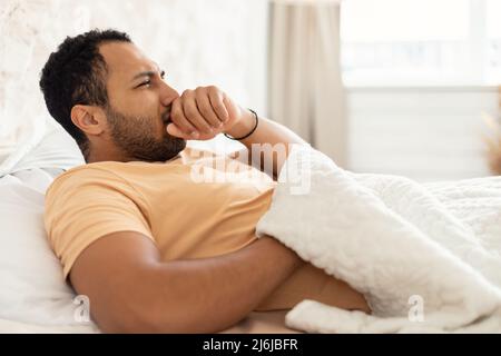 Malade arabe l'homme toussant dans le poing allongé dans la chambre moderne Banque D'Images